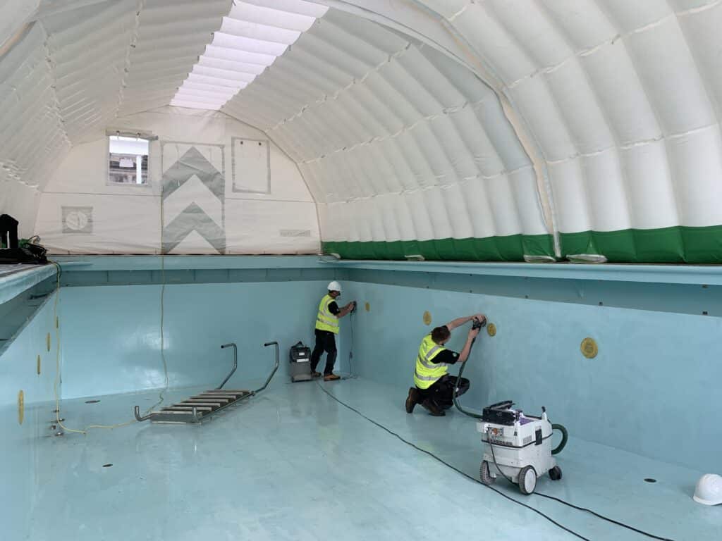 Operatives preparing the drained pool surface inside the Njordair work tent