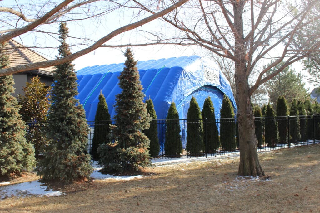 Njordair inflatable pool enclosure screened by garden conifers in Kansas City