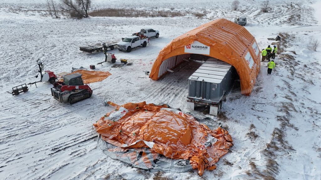 Aerial view of Njordair modules being positioned over the trailer-mounted frac tank in snow